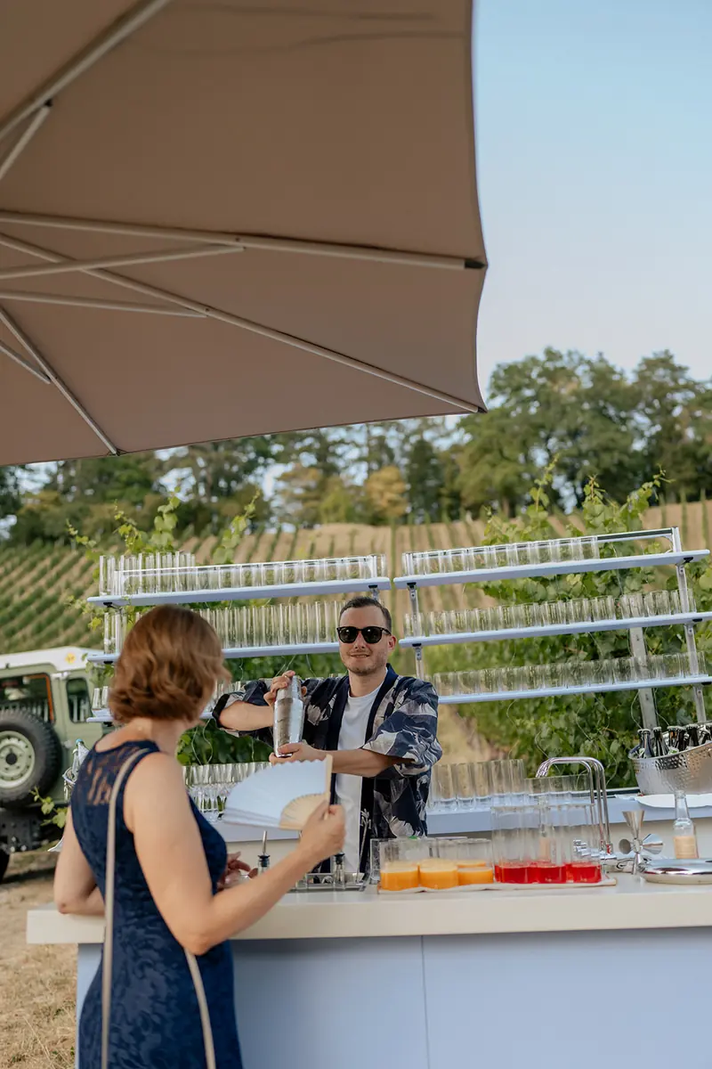 Bartender shaking a cocktail behind a mobile bar in a vineyard