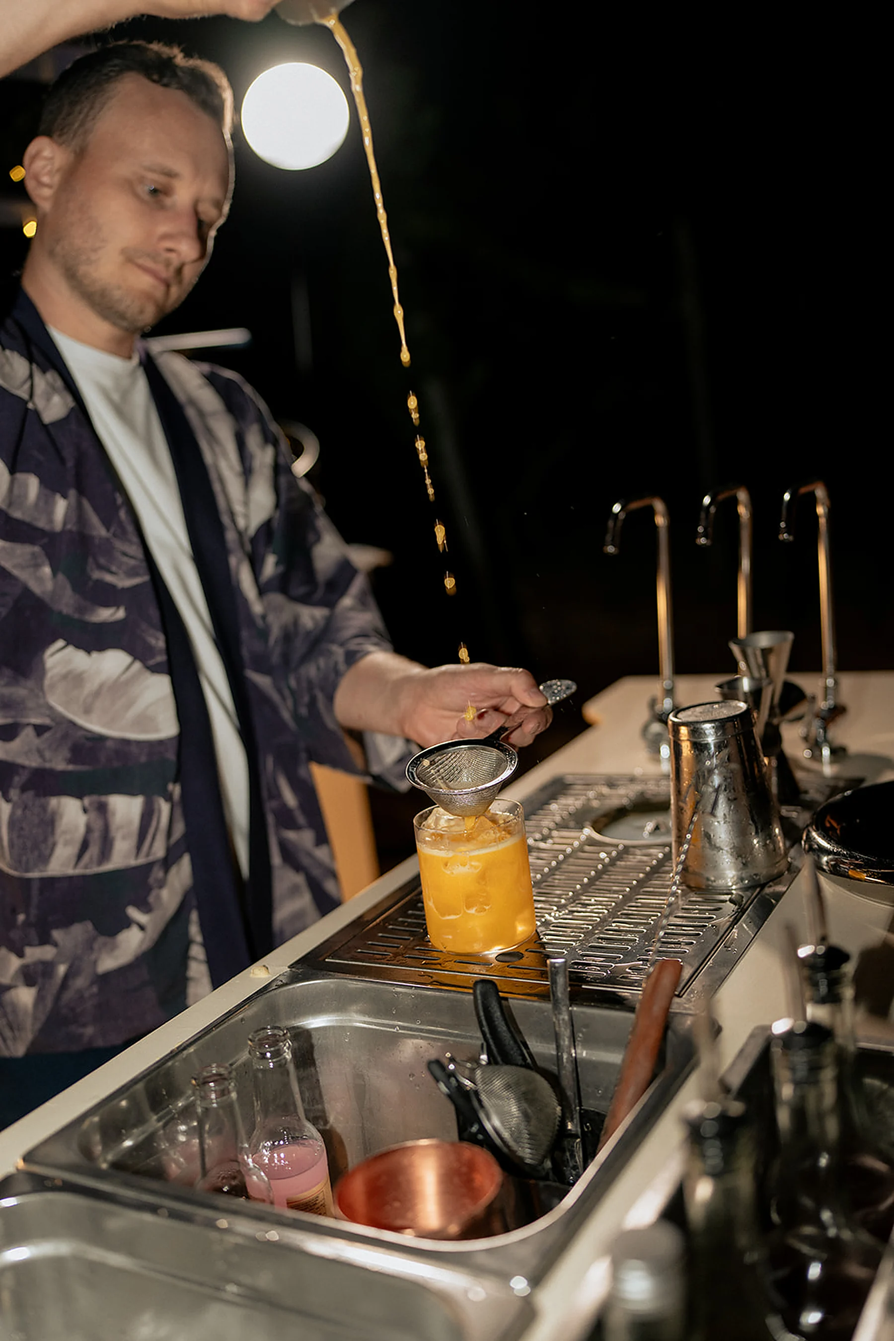 Bartender straining a freshly poured cocktail at a REDEFIN/ED mobile bar