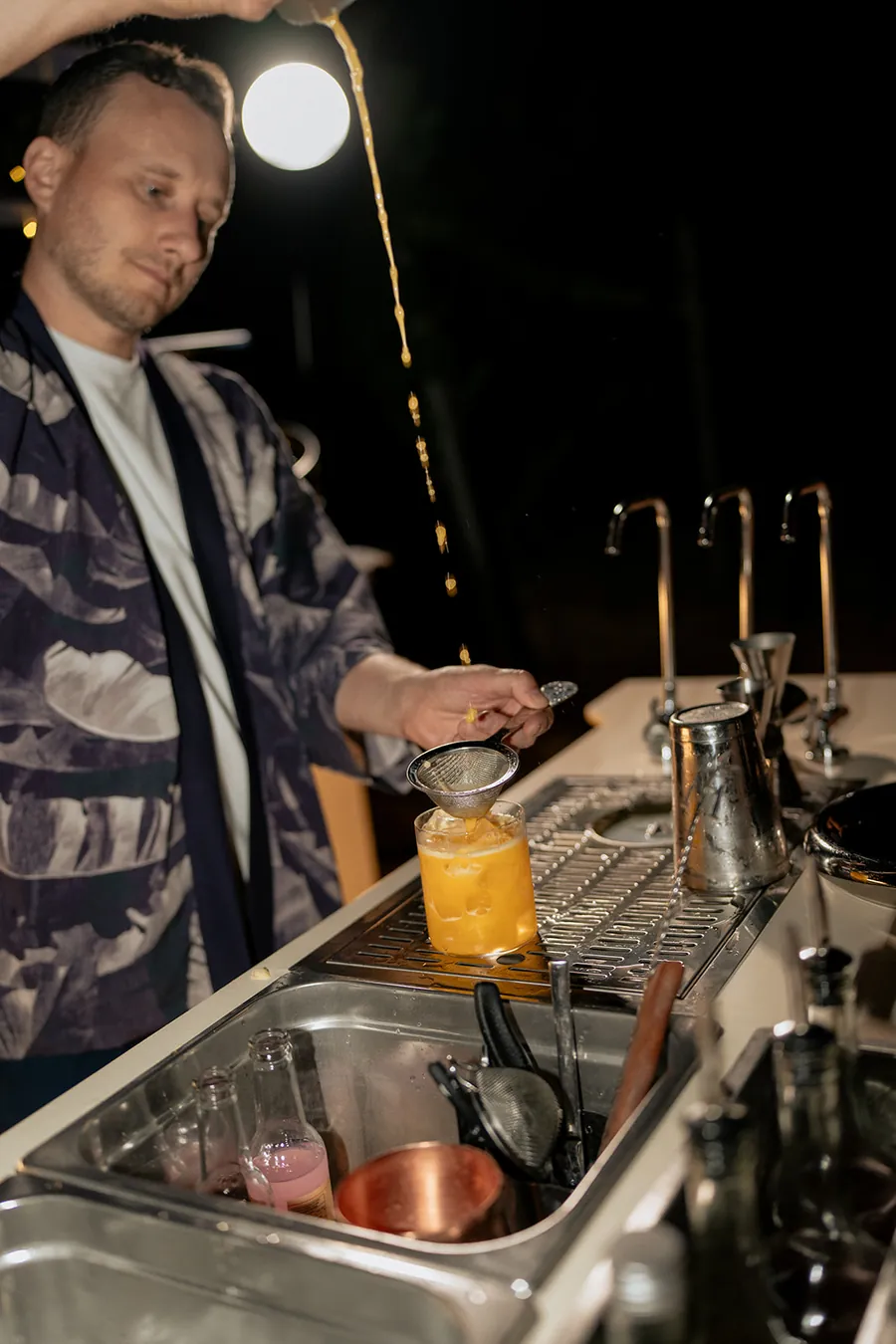 Bartender shaking and pouring cocktails at a REDEFIN/ED bar